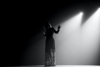 woman in black dress standing on stage