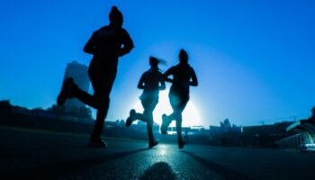 silhouette of three women running on grey concrete road