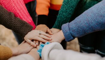 person in red sweater holding babys hand